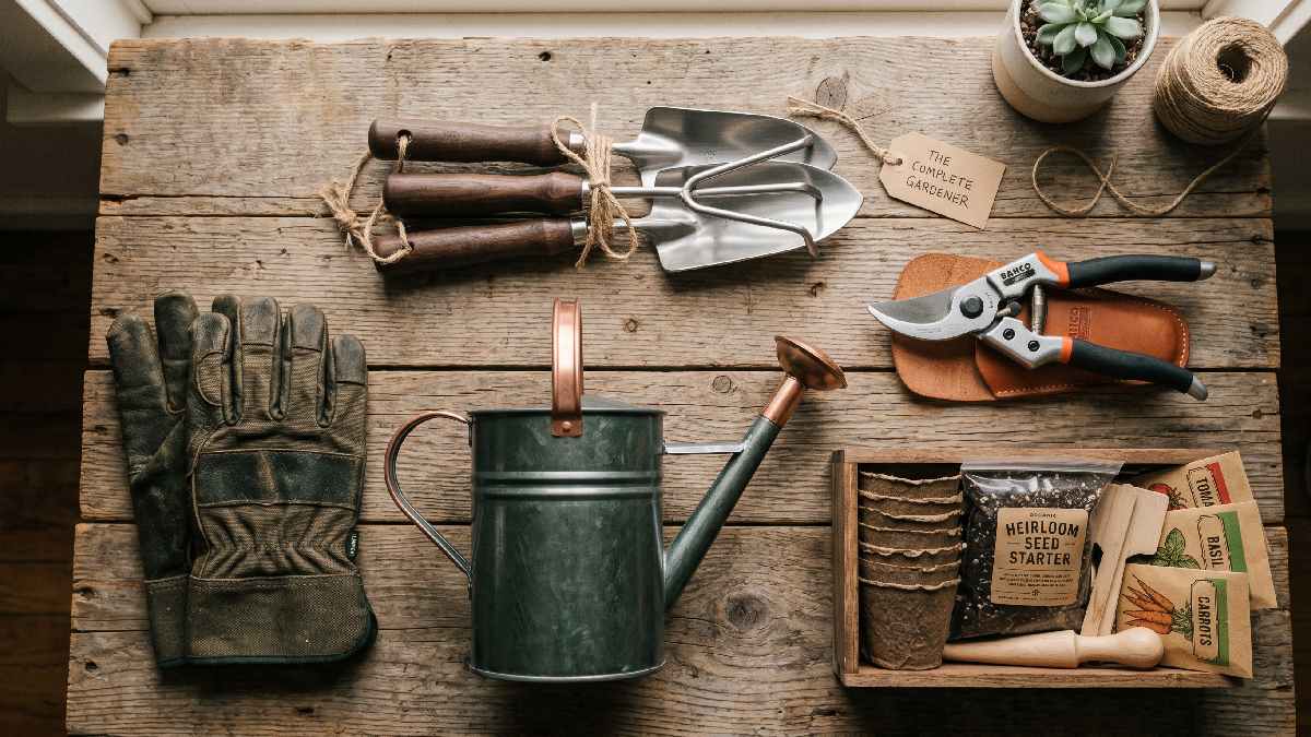 Practical gardening gifts for men including tool set, gloves, pruning shears, watering can, and seed kit on a wooden surface showing useful everyday gardening presents.